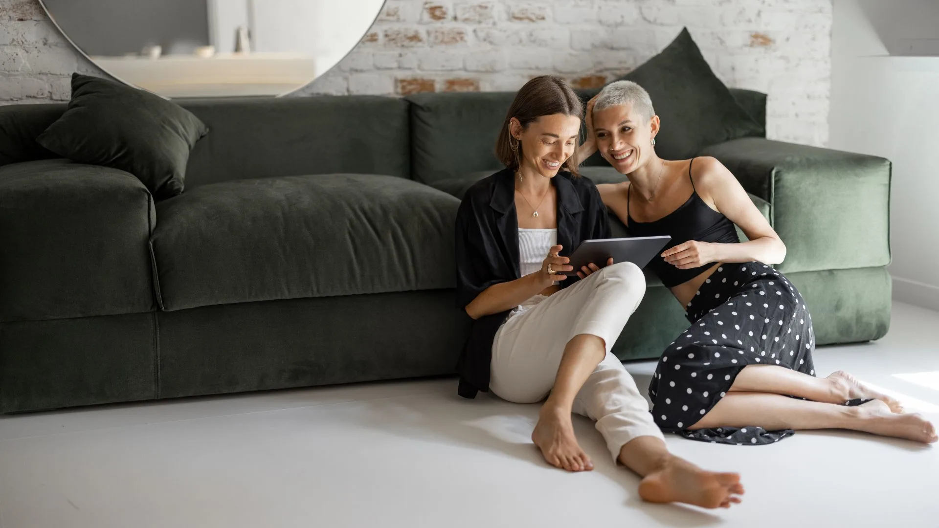 lgbt couple sitting on the floor of their living room while checking the tablet